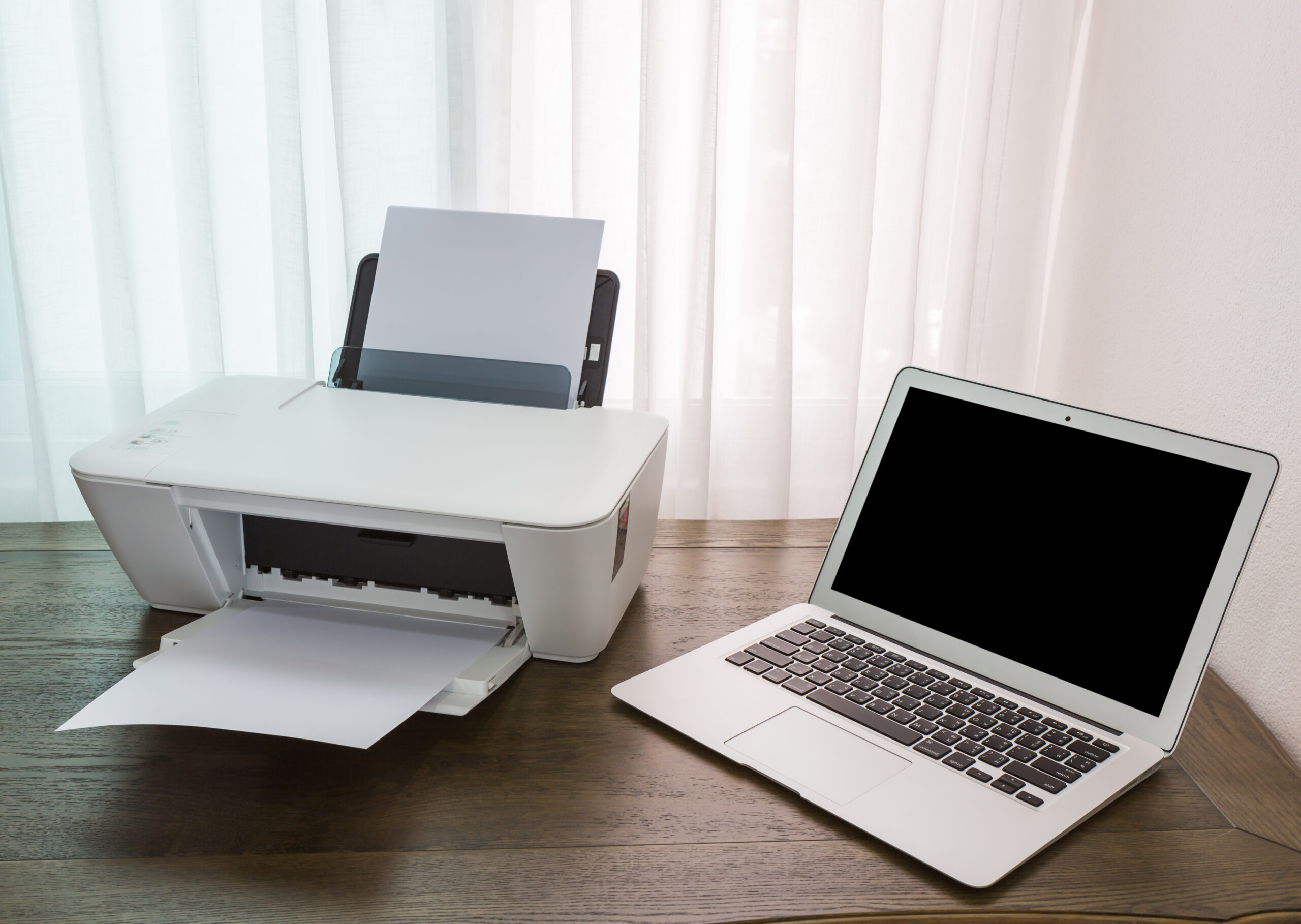 Laptop and printer on a wooden desk